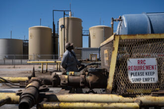 Brandon Horton, a driver for Allied Eagle Transports, monitors the transfer of a load of salt water, a byproduct of fracking, to a disposal site south of Midland, Texas, on June 25. Credit: Eli Hartman/The Texas Tribune