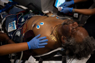 Robert Shipp, 75, of Bastrop, sweats while receiving treatment from Austin-Travis County EMS first responders inside an ambulance during a 102 degree day in Del Valle, Texas, on July 7, 2023. According to the EMS crew, he passed out while searching for car parts under the hot sun. Credit: Joe Timmerman/The Texas Tribune