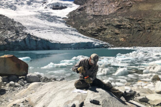 Researcher Emilio Mateo takes a rock sample in front of an iceberg-filled lake at the toe of Queshque Glacier, in the Cordillera Blanca, Peru. Credit: Evan Vega