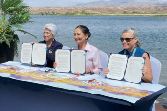 From left: Amelia Flores, Colorado River Indian Tribes chairwoman, Secretary of the Interior Deb Haaland and Arizona Gov. Katie Hobbs approve the tribe’s authority to lease, exchange or store its portion of Colorado River water. Credit: Noel Lyn Smith/Inside Climate News