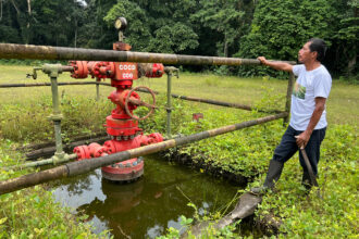 Anival Tanguila, a Quichua leader from the Corazón del Oriente Community, stands next to decommissioned Perenco oil infrastructure in the Ecuadorian Amazon on March 22, 2023. Credit: Katie Surma/Inside Climate News