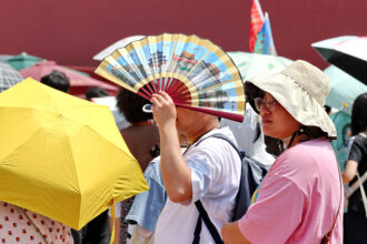 Tourists shield themselves from the sun while visiting the Palace Museum during a heat wave on July 6 in Beijing, China. Credit: VCG via Getty Images