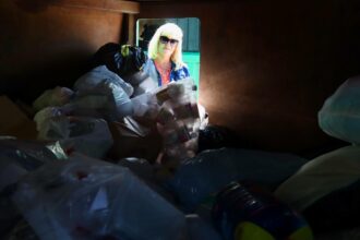 Jan Dell, founder of The Last Beach Cleanup and a chemical engineer, examines the contents of a large container of bagged plastics at a Houston Recycling Collaboration all-plastics recycling depository in the Houston community of Kingwood in September. Credit: James Bruggers/Inside Climate News