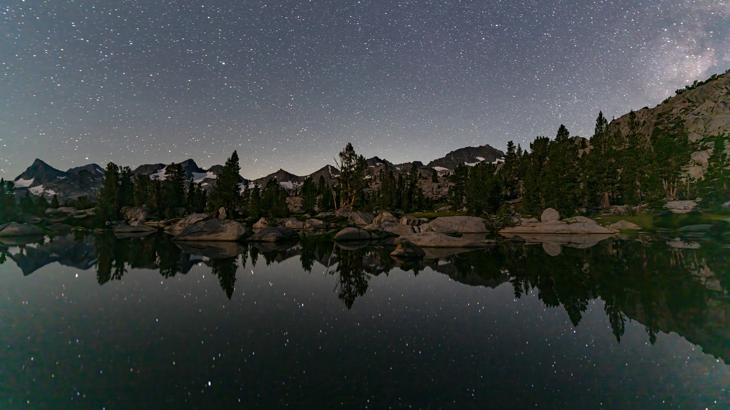 Stars and the Milky Way reflect off a small lake in the Ansel Adams Wilderness near the PCT. Credit: Bing Lin/Inside Climate News