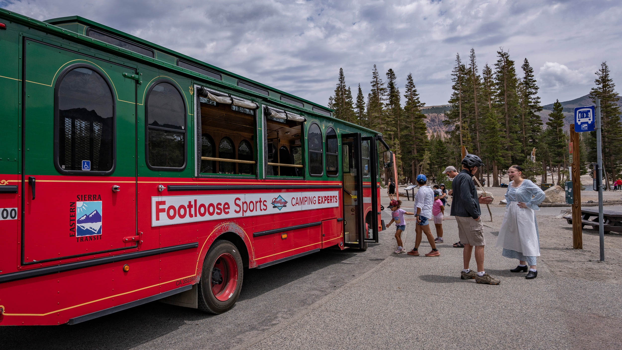 A costumed employee on the Mammoth Lakes free trolley talks to hikers about the town's history and sightseeing hotspots. Credit: Bing Lin/Inside Climate News